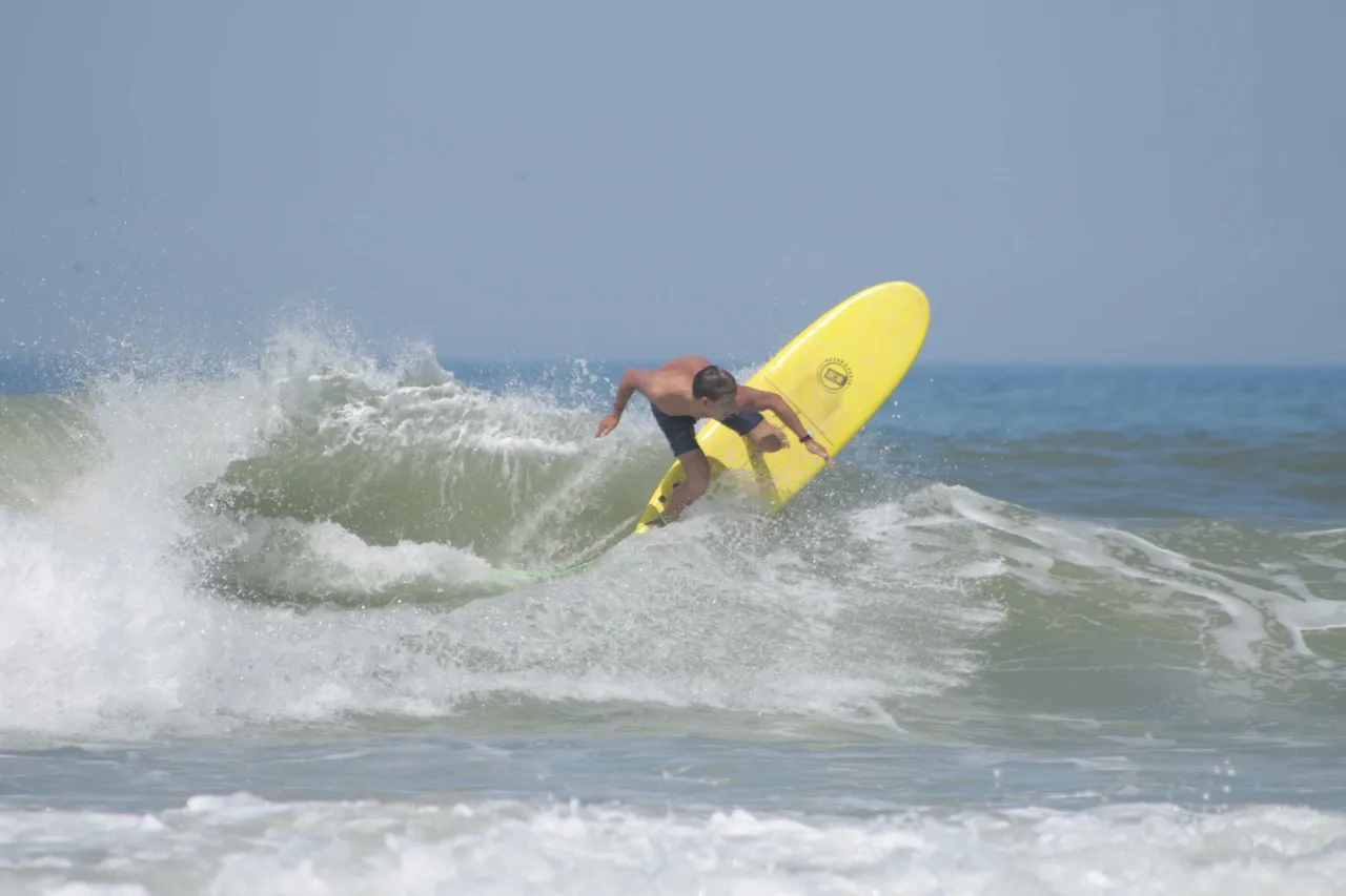 Ben throwing a shaka hand signal whilst coaching a group of intermediates in smaller waves